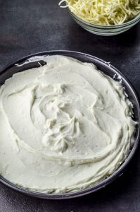 ricotta spread on top of kataifi in a round pan