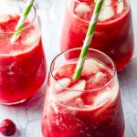 three glasses filled with date sweetened raspberry lemonade with green and white paper straws
