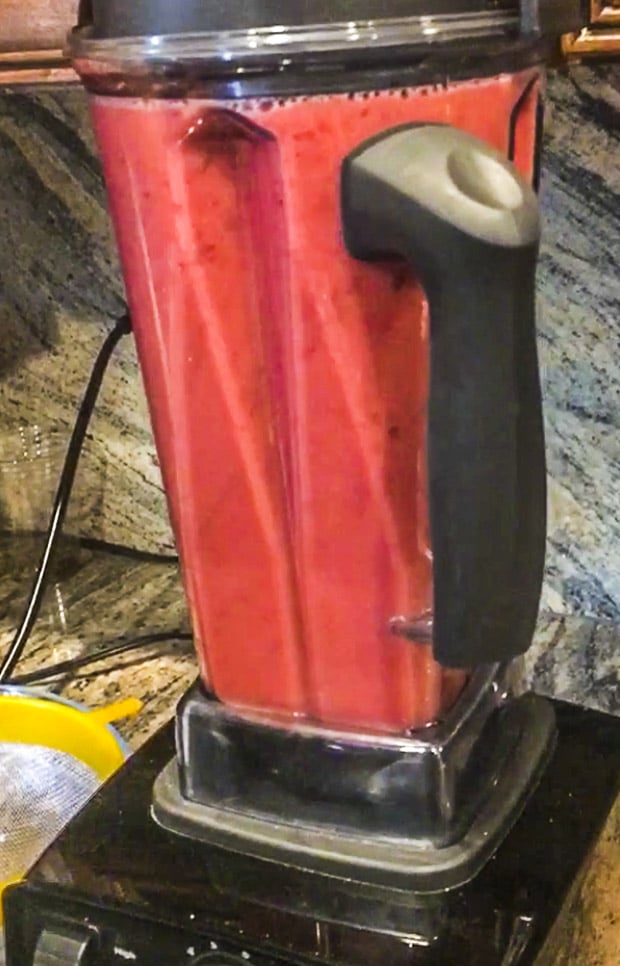 A large high speed blender filled with raspberry lemonade