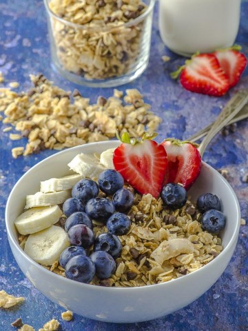 A bowl of nut free coconut granola with strawberries and blueberries