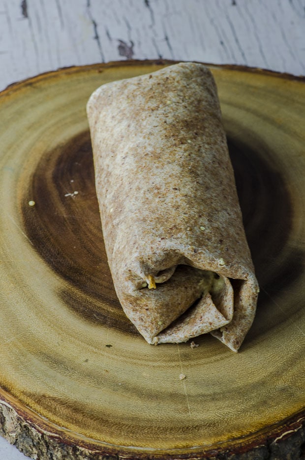 A vegan tempeh breakfast burrito on a wood surface