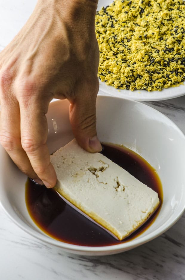 A slice of tofu in a bowl with soy sauce