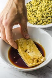 Dipping tofu in soy sauce for a veggie sandwich