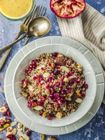 Bird's eye view of a plate filled with a quinoa salad topped with pomegranates and nuts