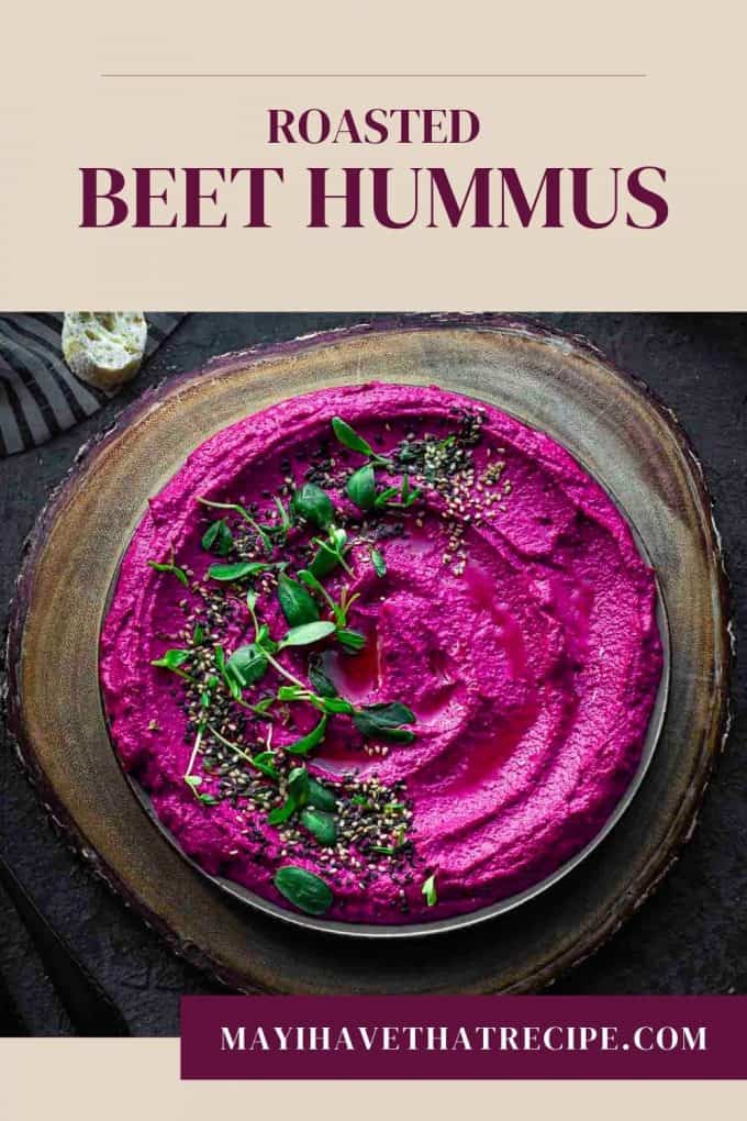 An overhead view of roasted beet hummus garnished on a wood platter
