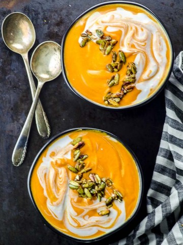Bird's eye view of two black bowls filled with coconut carrot ginger soup