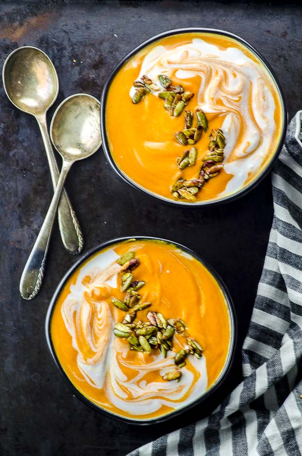 Bird's eye view of two black bowls filled with coconut carrot ginger soup