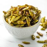 a white bowl filled with cinnamon ginger spiced pumpkin seeds