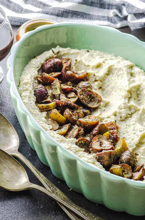 Side close-up view of a baking dish with mashed cauliflower and herbed chestnuts