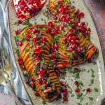 Birds eye view of two hasselback butternut squash topped with cranberries, pecans and pomegranates