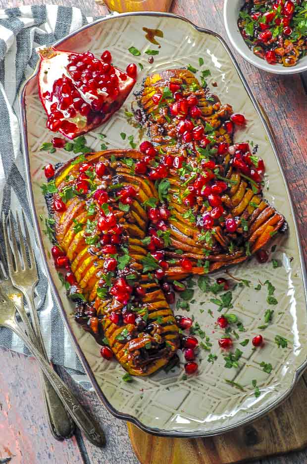 Birds eye view of two hasselback butternut squash topped with cranberries, pecans and pomegranates