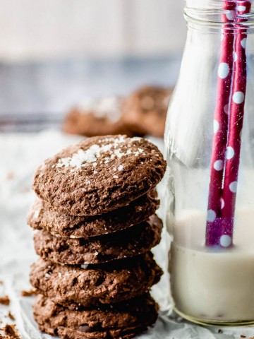 Side view of a pile of double chocolate chip cookies nest to a bottle of milk