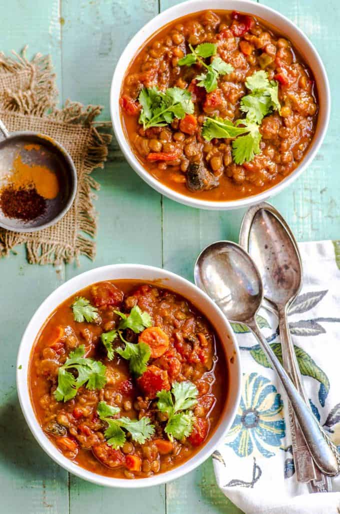 Two bowls of vegetarian chili with two spoons overlapping each other