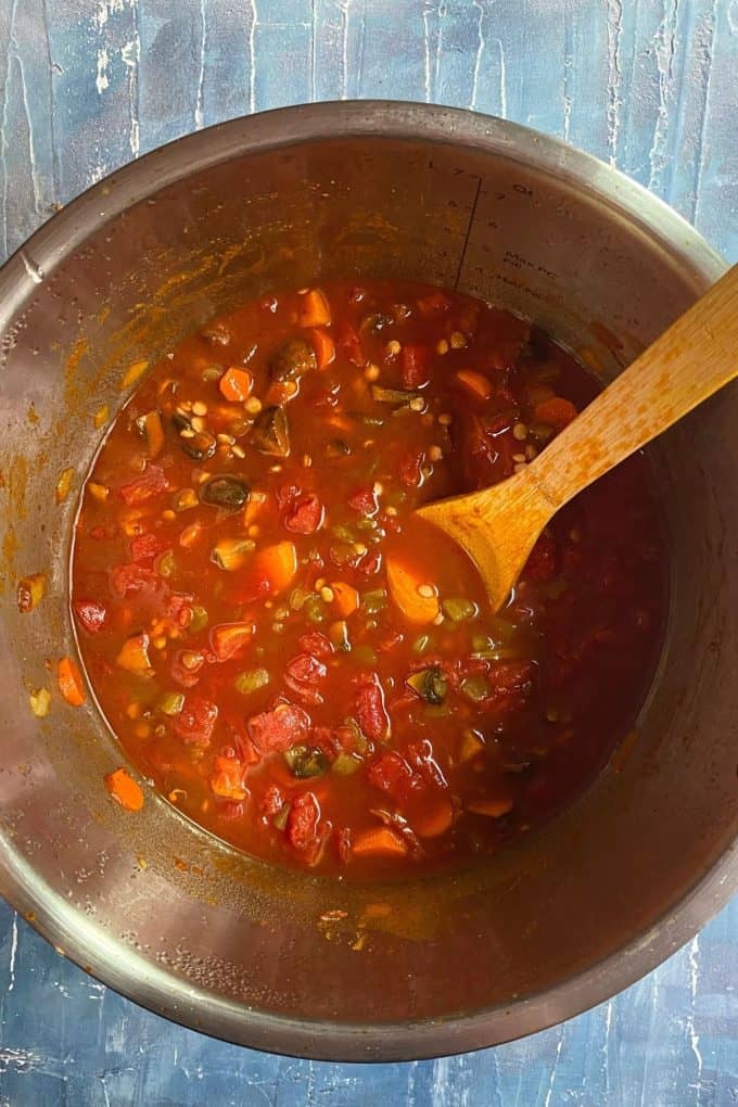 Vegetarian chili in a big pot with a wooden spoon
