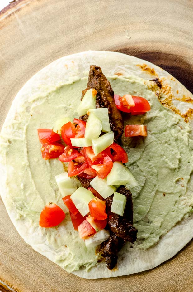 taco shell with avocado tahini spread and portabella shawarma, tomatoes and cucumbers for veggie tacos