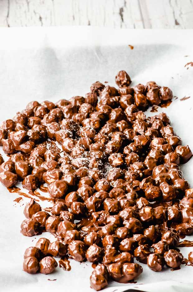 Spreading chocolate covered hazelnuts on a baking sheet lines with parchment paper