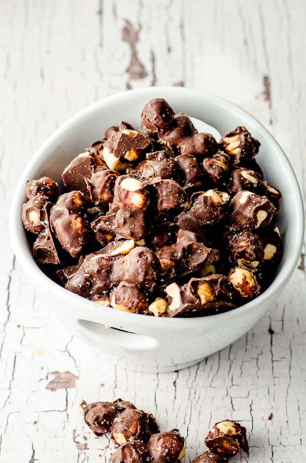 Chocolate covered hazelnuts in a white bowl. One of our vegetarian Passover recipes.