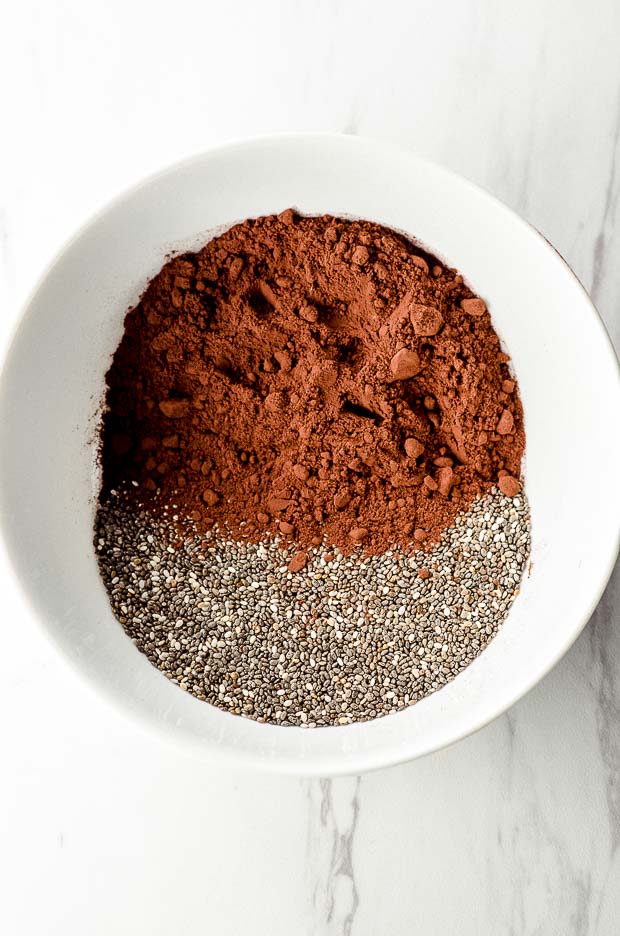 Chia seeds and cocoa powder side by side in a white bowl