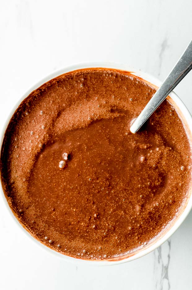 Chocolate chia seed pudding base in white bowl with spoon inside
