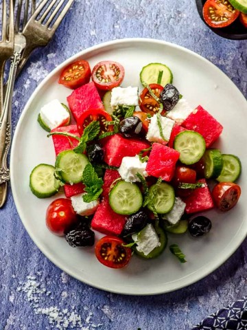 Bird's eye view of a white plate with cucumber feta watermelon salad
