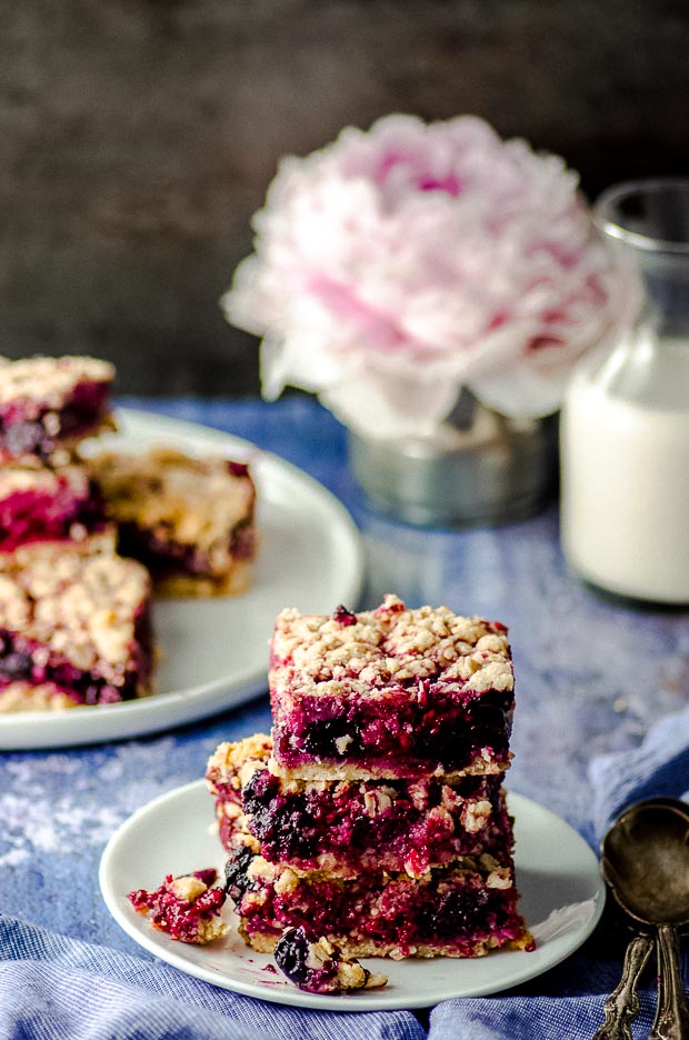 Side view of Vegan Gluten Free Blueberry Raspberry Bars stacked on a white plate