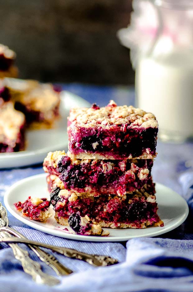 Close up view of Vegan Gluten Free Blueberry Raspberry Bars stacked on a white plate