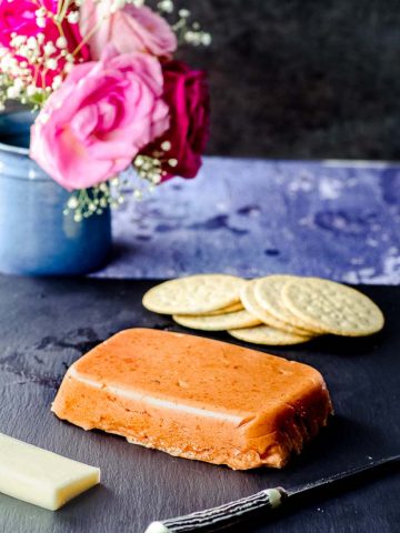 Dulce de membrillo on a black serving board with some crackers in the background