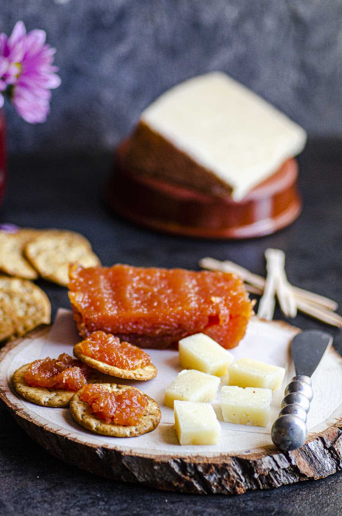 A wood board with diced manchego cheese and crackers with membrillo
