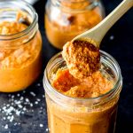 Scooping some romesco sauce out of a glass jar