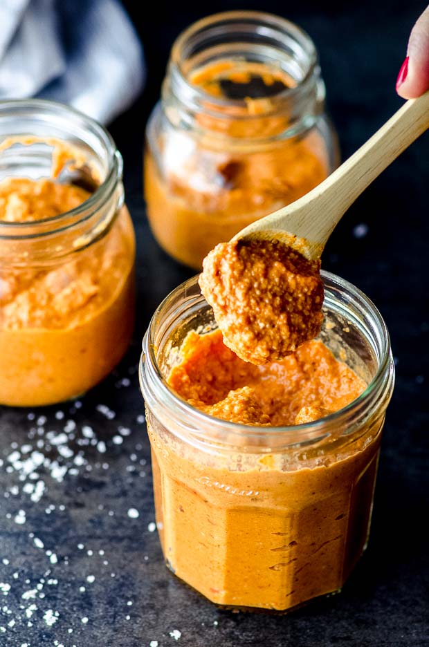 Scooping some romesco sauce out of a glass jar. One of our vegetarian Passover recipes.