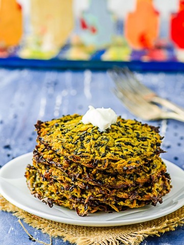 Butternut squash Latkes staked on a white plate with a Menorah in the background