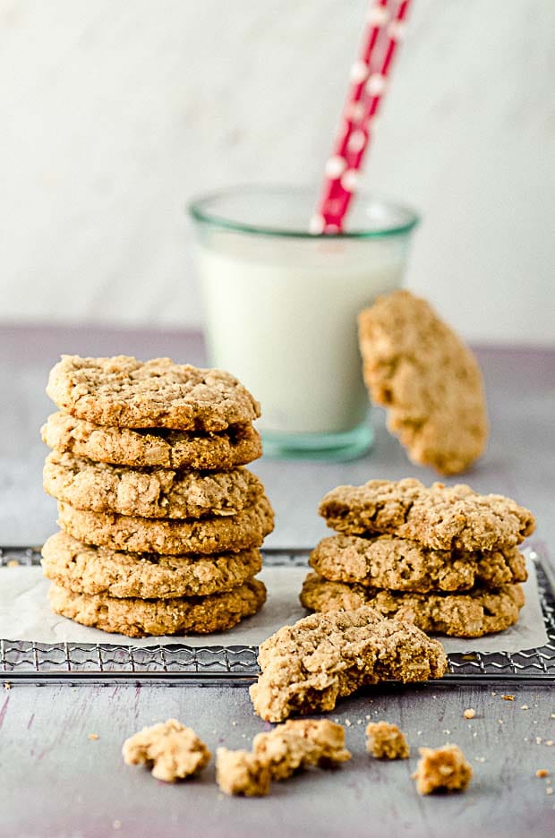 Two piles of peanut butter oatmeal cookies and a glass of milk in the background