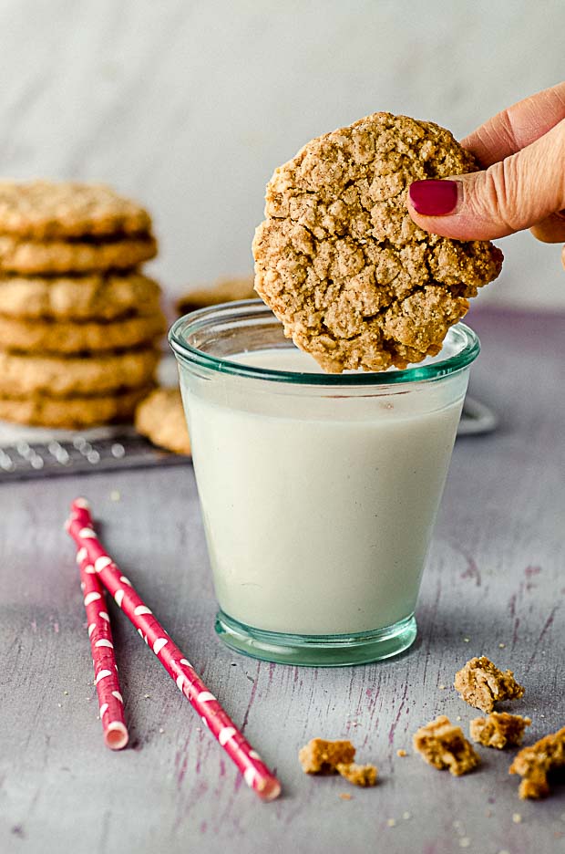 dipping a peanut butter oatmeal cookies a glass of milk