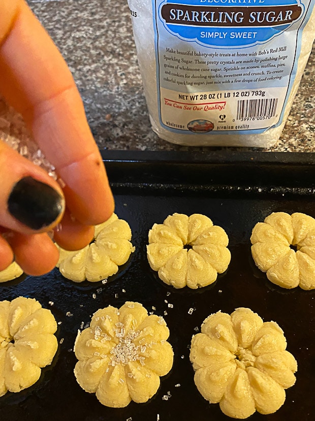 sprinkling sparkling sugar on shaped vegan butter cookies