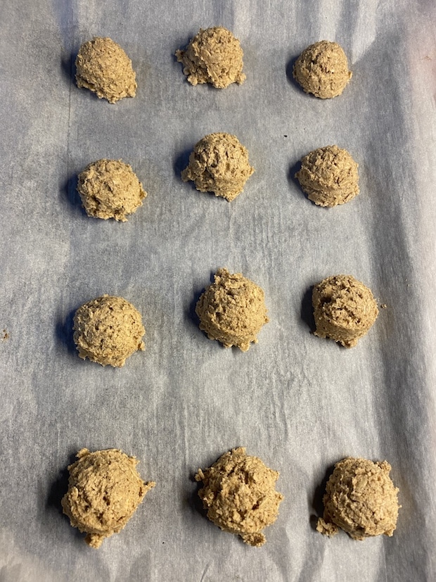 Peanut butter oatmeal cookie dough balls on a parchment lined baking sheet