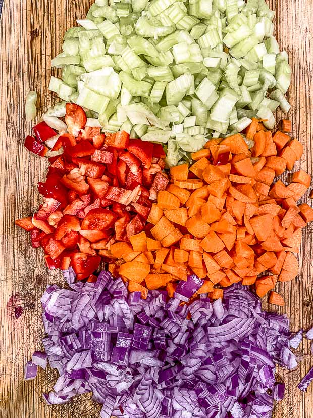 Diced celery, red pepper, carrots and onions in a wood cutting board ready to make black bean soup