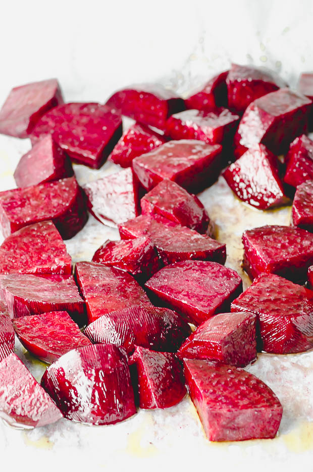 Raw cut beets on a baking sheet lined with parchment paper ready to be cooked