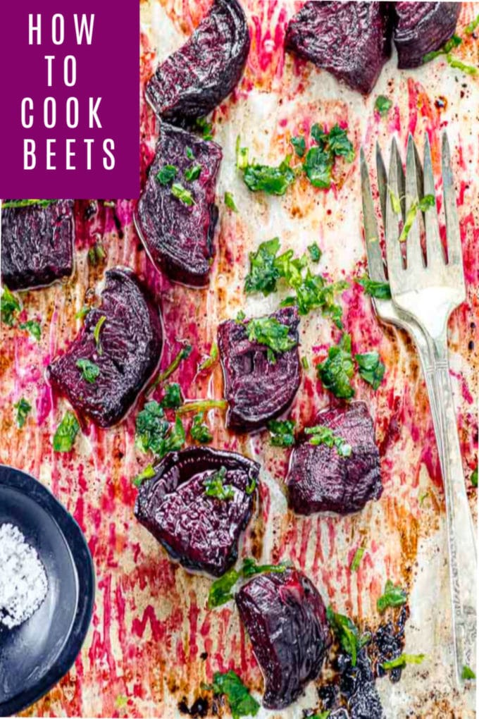 Bird's eye view of a baking sheet with cut roasted beets and a small bowl will flaky salt.