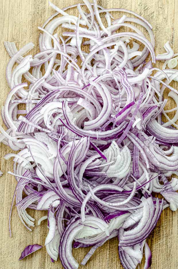 Sliced red onion on a wood cutting board ready to make pickled onions