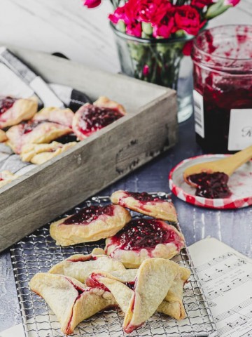 Raspberry hamantaschen set up on a table with a flower vase in the background