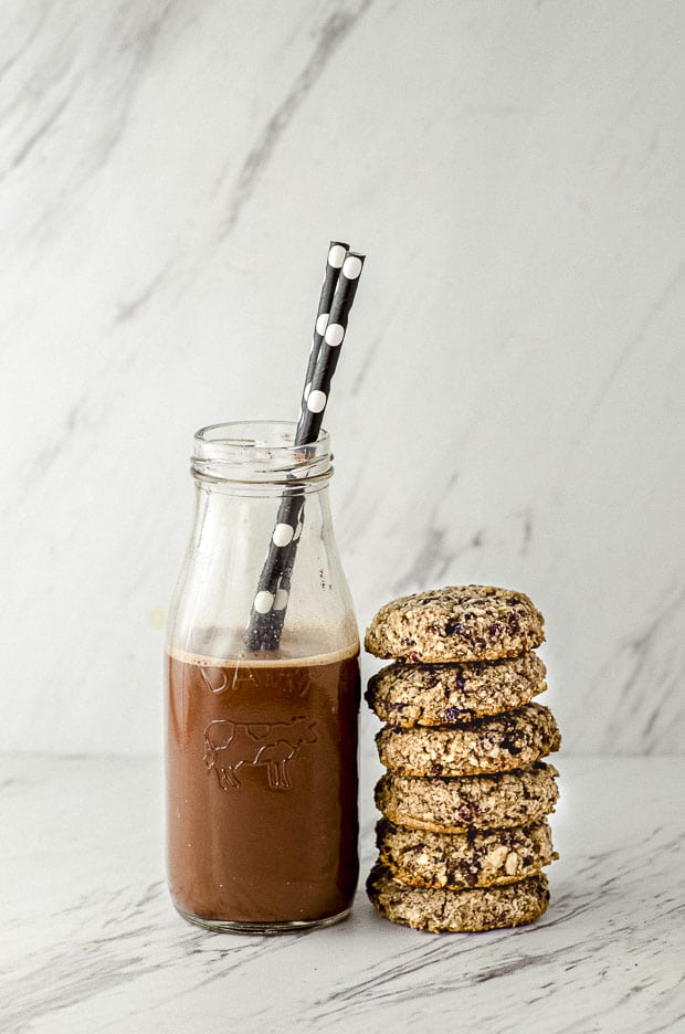A pile of 6 cookies leaning against a small bottle of chocolate milk