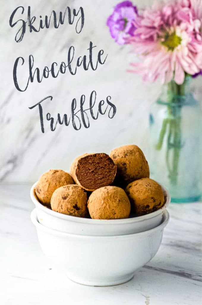 Side view of two staked bowls filled with dark chocolate truffles with a vase with flower in the background with a sign reading skinny chocolate truffles