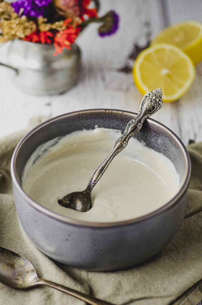 Side view of a bowl of tahini sauce with a spoon inside