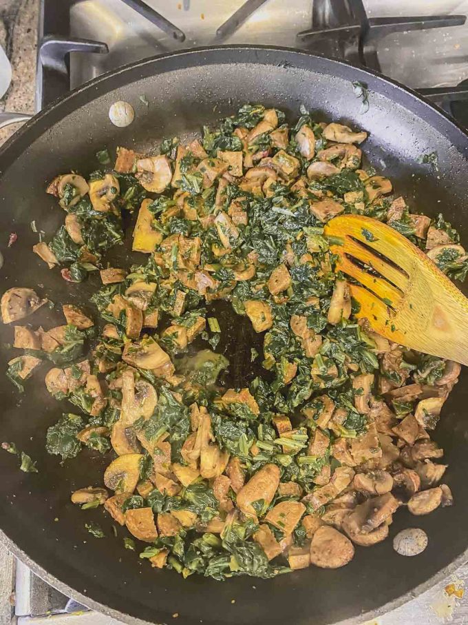 Sauteing mushrooms and veggie sausage and spinach in a skillet