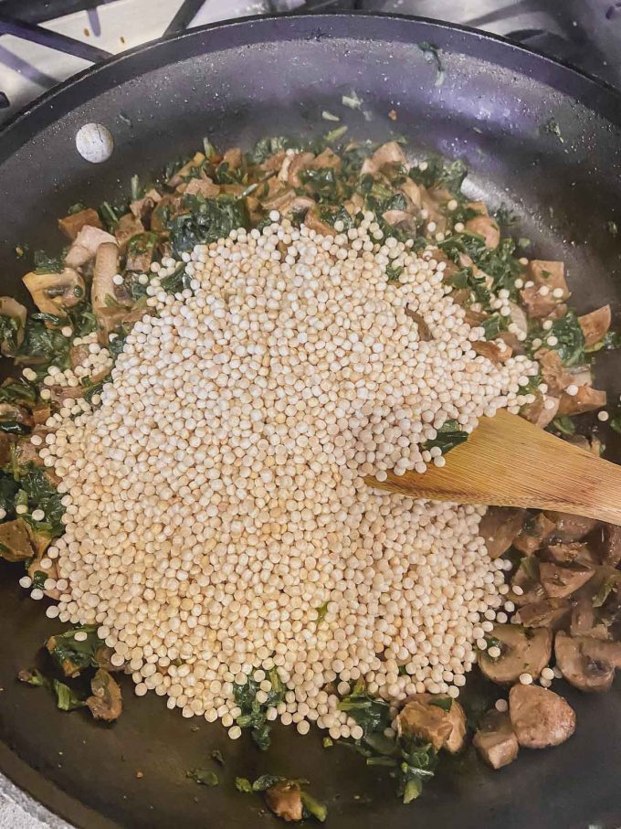 Adding Israeli couscous to mushrooms, sausage and spinach