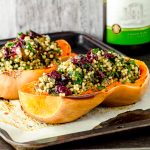 Side view of two roasted butternut squash halves stuffed with Israeli couscous and topped with dried cranberries