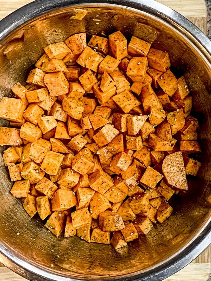 Cut up uncooked sweet potato cubes in a bowl covered with olive oil and za'atar