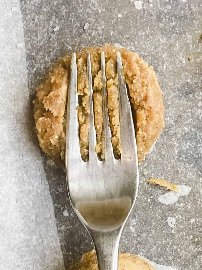 flattening a peanut butter cookie with a fork
