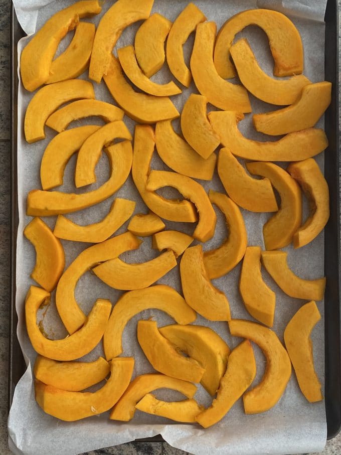 Sliced and peeled thing wedges of pumpkin on a baking sheet