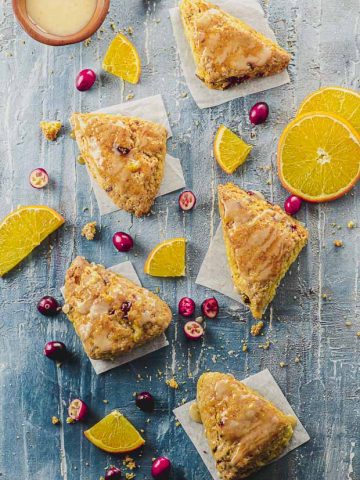 Overhead view of five orange cranberry scones on a blue surface